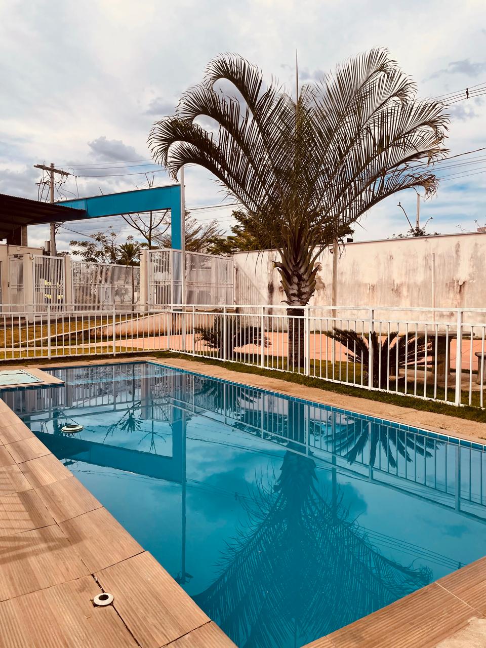 Piscina do condomínio com deck e jardim